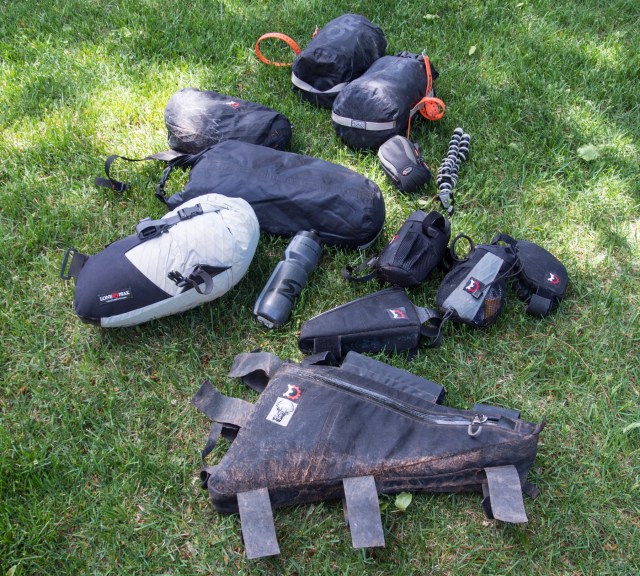 All the gear, off-bike, including frame pack, seat pack, three 10 liter day bags, a handlebar front pocket, two top tube packs, and two handlebar packs